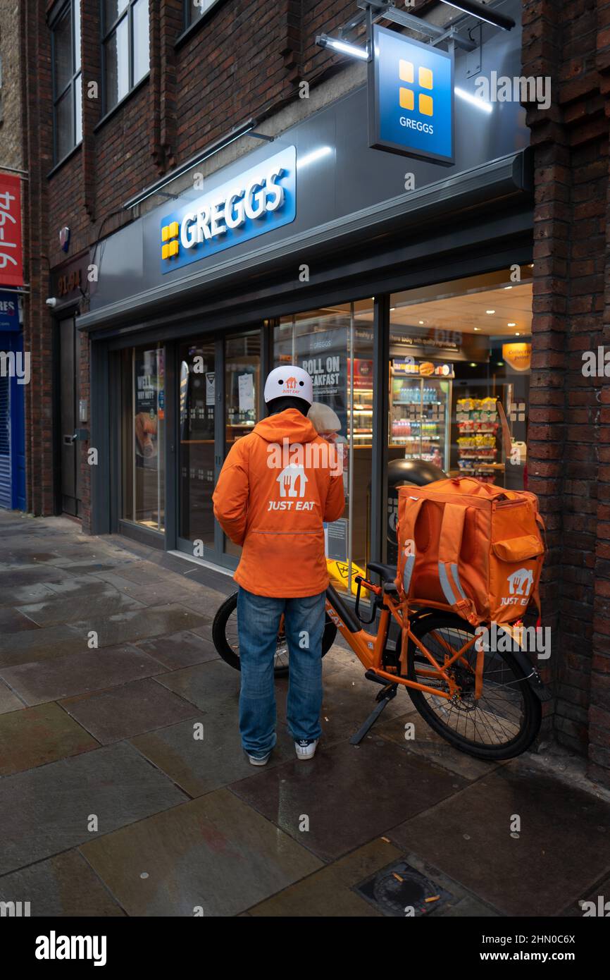 Una persona di consegna di Just Eat si prepara ad entrare in Greggs per ritirare un ordine per la consegna. Preso presto la Domenica mattina a Lower Marsh, Waterloo Londra Foto Stock