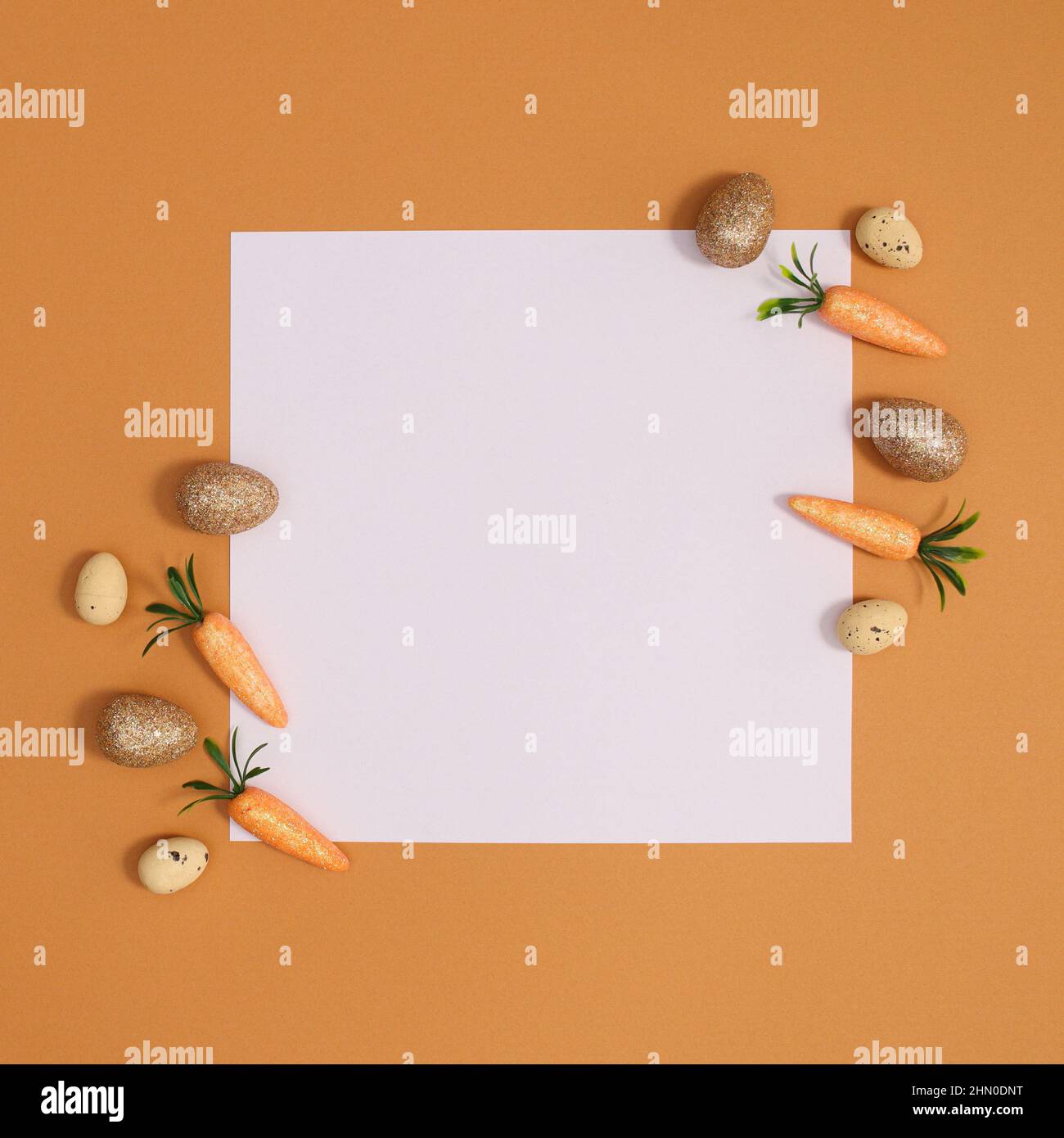 Organizzazione creativa di Pasqua minima con carote e uova d'oro intorno carta di nota. Composizione della disposizione piatta. Foto Stock