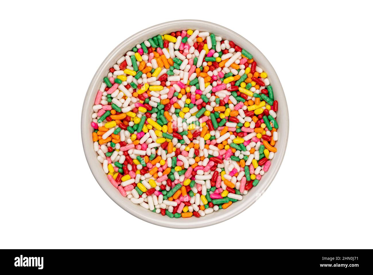 Vista dall'alto di spruzzi di zucchero arcobaleno multicolore in tazza di ceramica bianca su sfondo bianco con percorso di taglio. Foto Stock