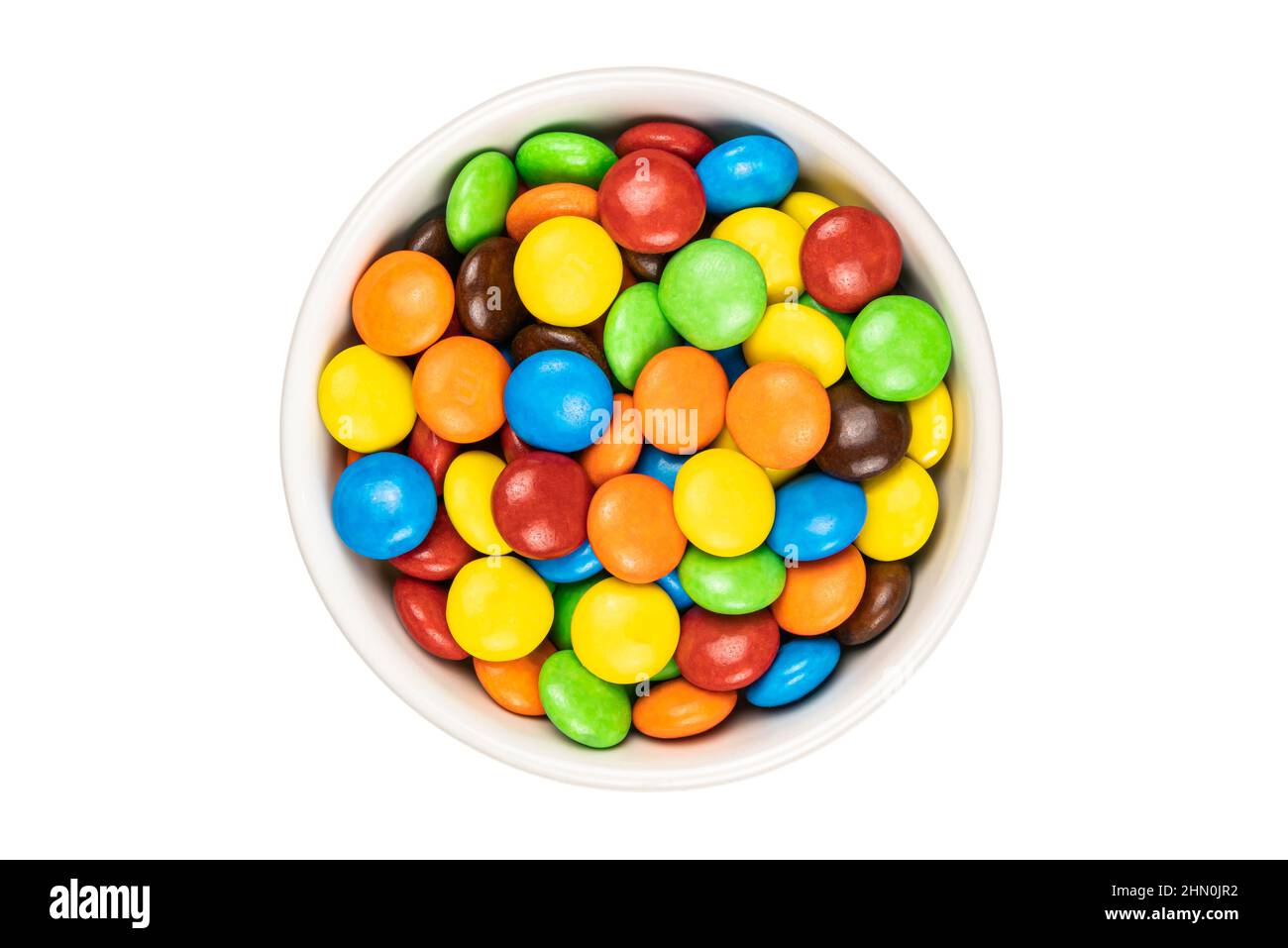 Parte superiore di caramelle a forma di bottoni di cioccolato multicolore in tazza di ceramica bianca su sfondo bianco con percorso di taglio. Foto Stock