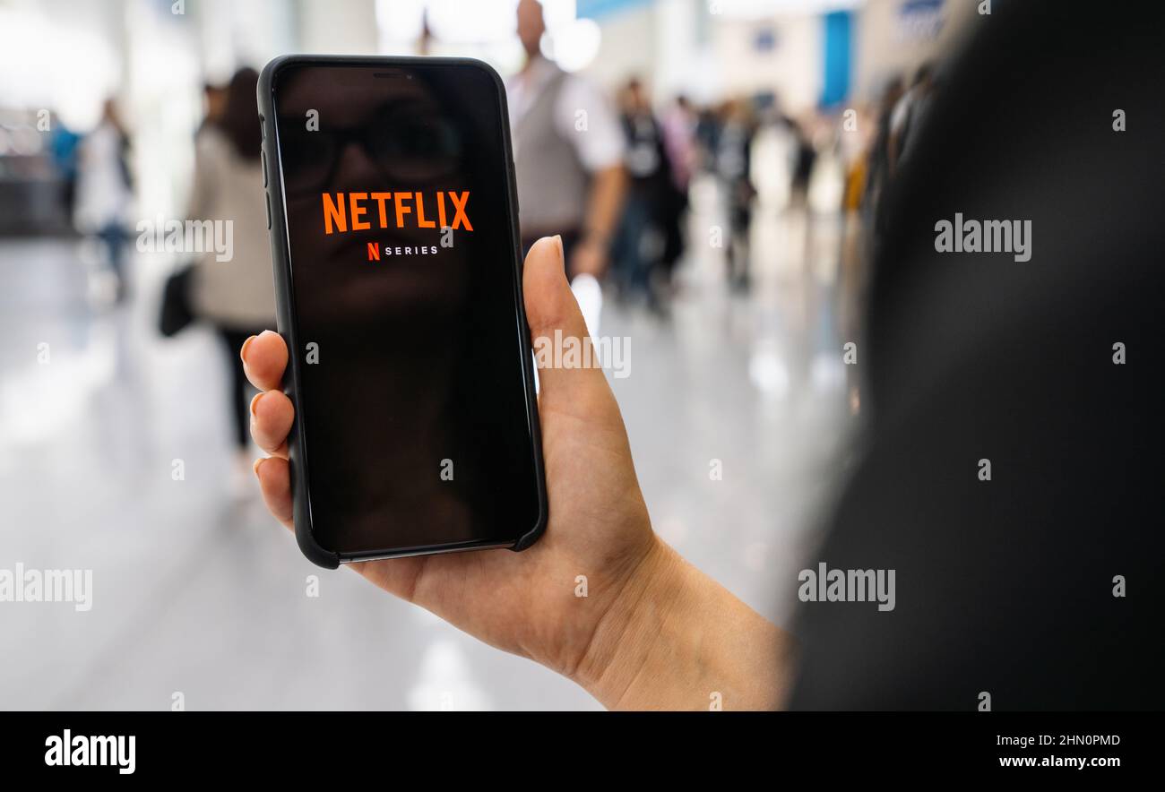 Applicazione Netflix su iPhone Apple. La giovane donna sta navigando nella videoteca di film cosa guardare. Foto Stock