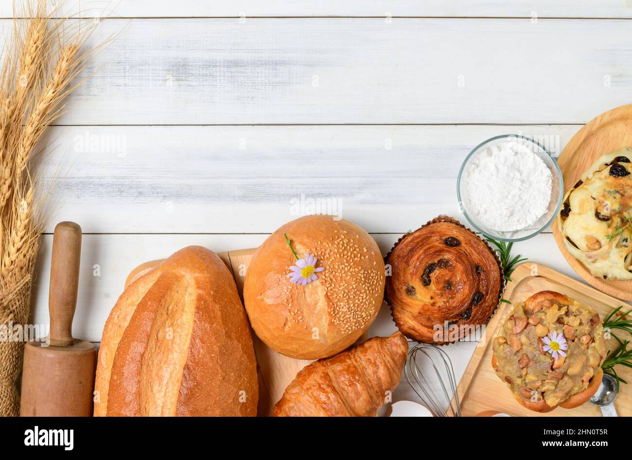 Pane fatto in casa o panino su sfondo di legno, croissant con pasta di Sourdough e pasticceria danese, colazione e prodotti da forno Foto Stock