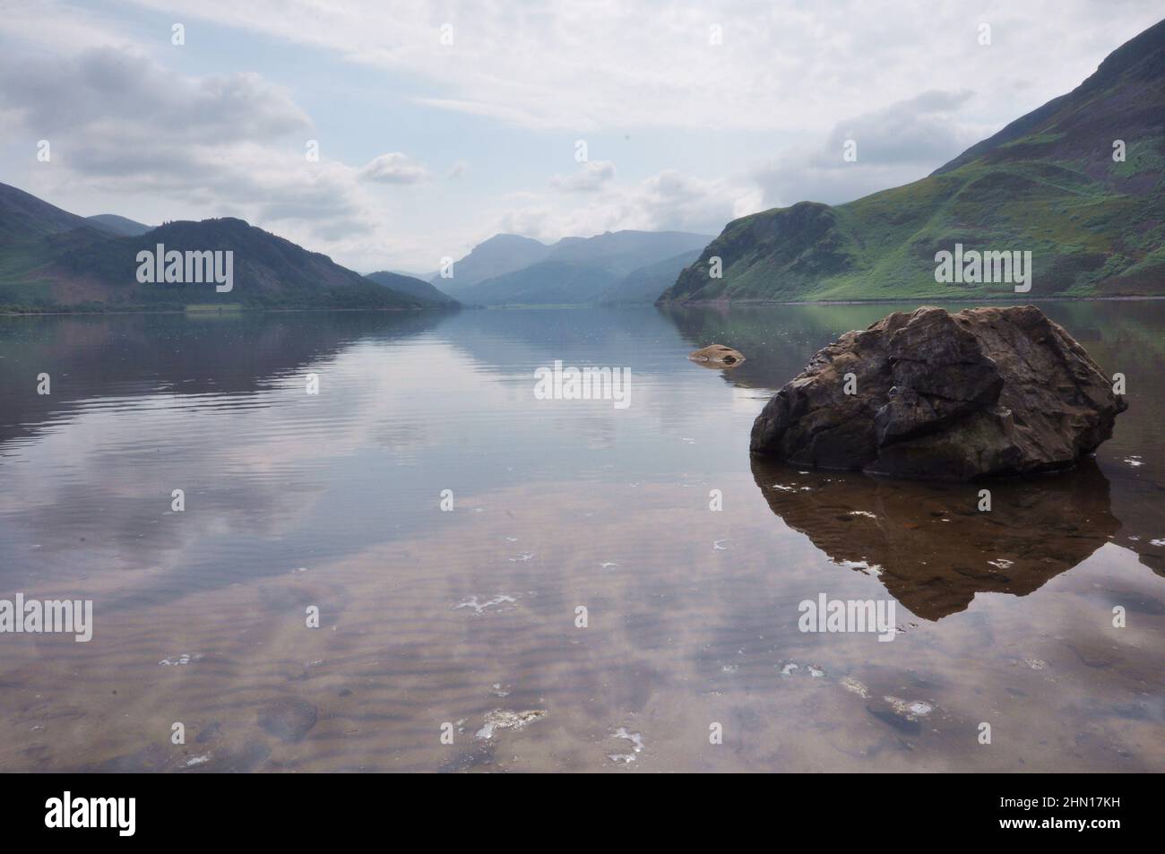 Veduta del lago Ennerdale nel distretto del lago, Regno Unito con cielo sovrastato e roccia in primo piano. Foto Stock