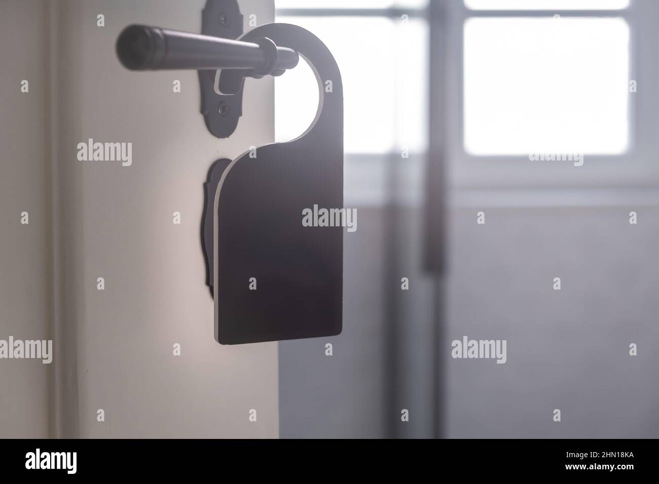 Appendiabiti in camera vuoto. Etichetta nera sul pomello della portiera posteriore aperta, vista ravvicinata. Porta bianca in legno, interno camera sfocata Foto Stock