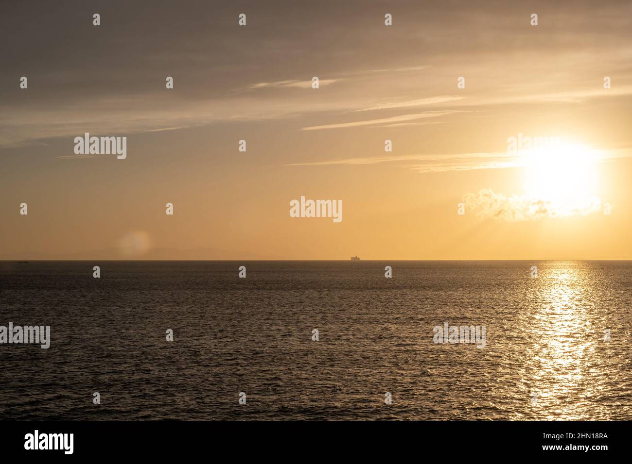 Tramonto sull'isola di Mykonos, Cicladi, Grecia, sole dorato colori il cielo arancione, giallo e rendere Mikonos mare scintilla. Foto Stock