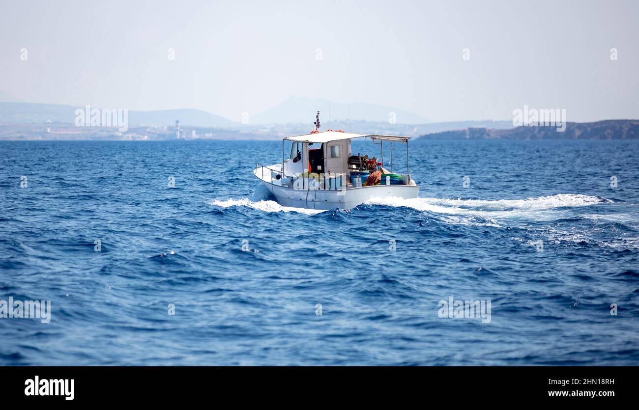 La barca da pesca naviga in mare ondulato Egeo, avvicinandosi all'isola, cielo blu sfondo. CICLADI Grecia. Foto Stock