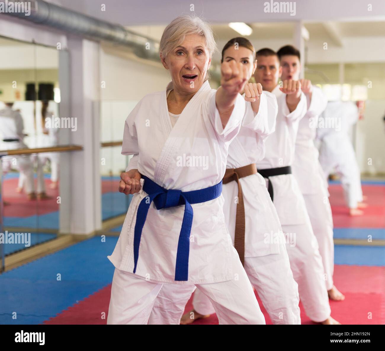 Lezione di gruppo in karate o taekwondo in palestra. Colpi di pratica Foto Stock