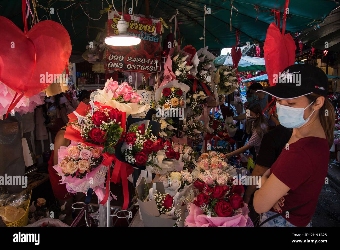 Bangkok, Tailandia. 13th Feb 2022. I clienti thailandesi che indossano maschere protettive per il viso selezionano mazzi di fiori per San Valentino presso un mercato dei fiori Pak Klong Talad a Bangkok. Credit: SOPA Images Limited/Alamy Live News Foto Stock