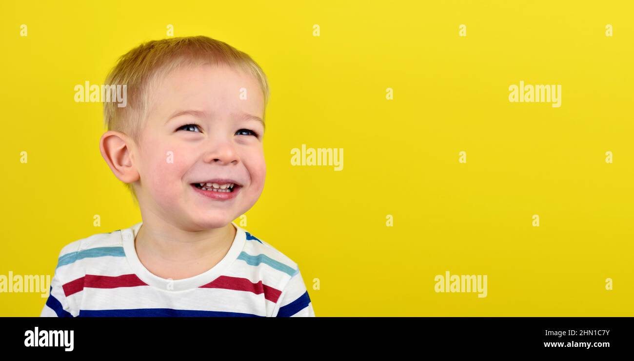 Ragazzo sorridente felice su sfondo colorato. Ritratto di un bel ragazzo europeo di due anni su sfondo giallo. Spazio di copia per il testo. Foto Stock