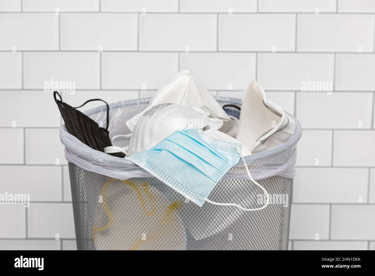 Maschere facciali in lattina spazzatura. Il COVID-19 copre il mandato, lo smaltimento e il requisito. Foto Stock