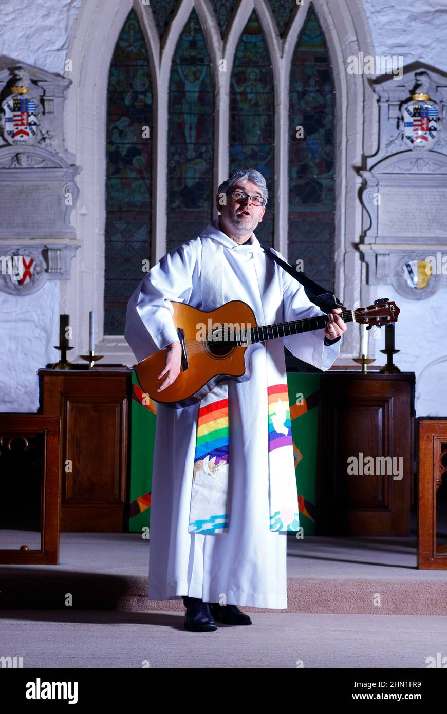 Il reverendo Bob Bailey suona la chitarra durante uno dei suoi servizi e cerimonie della chiesa alla chiesa di St Mary a Kippax, West Yorkshire UK Foto Stock