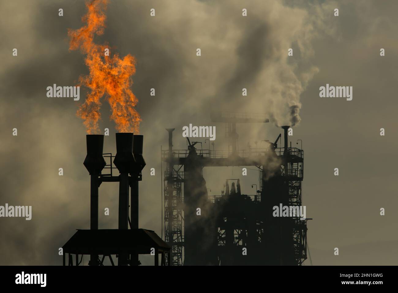 Camini industriali pesanti che producono fumo e fuoco. Illustrazione dell'inquinamento atmosferico e danni agli organi respiratori. Riscaldamento globale e industria del carbone Foto Stock