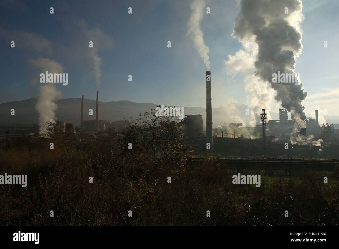 Camini industriali pesanti che producono fumo e fuoco. Illustrazione dell'inquinamento atmosferico e danni agli organi respiratori. Riscaldamento globale e industria del carbone Foto Stock