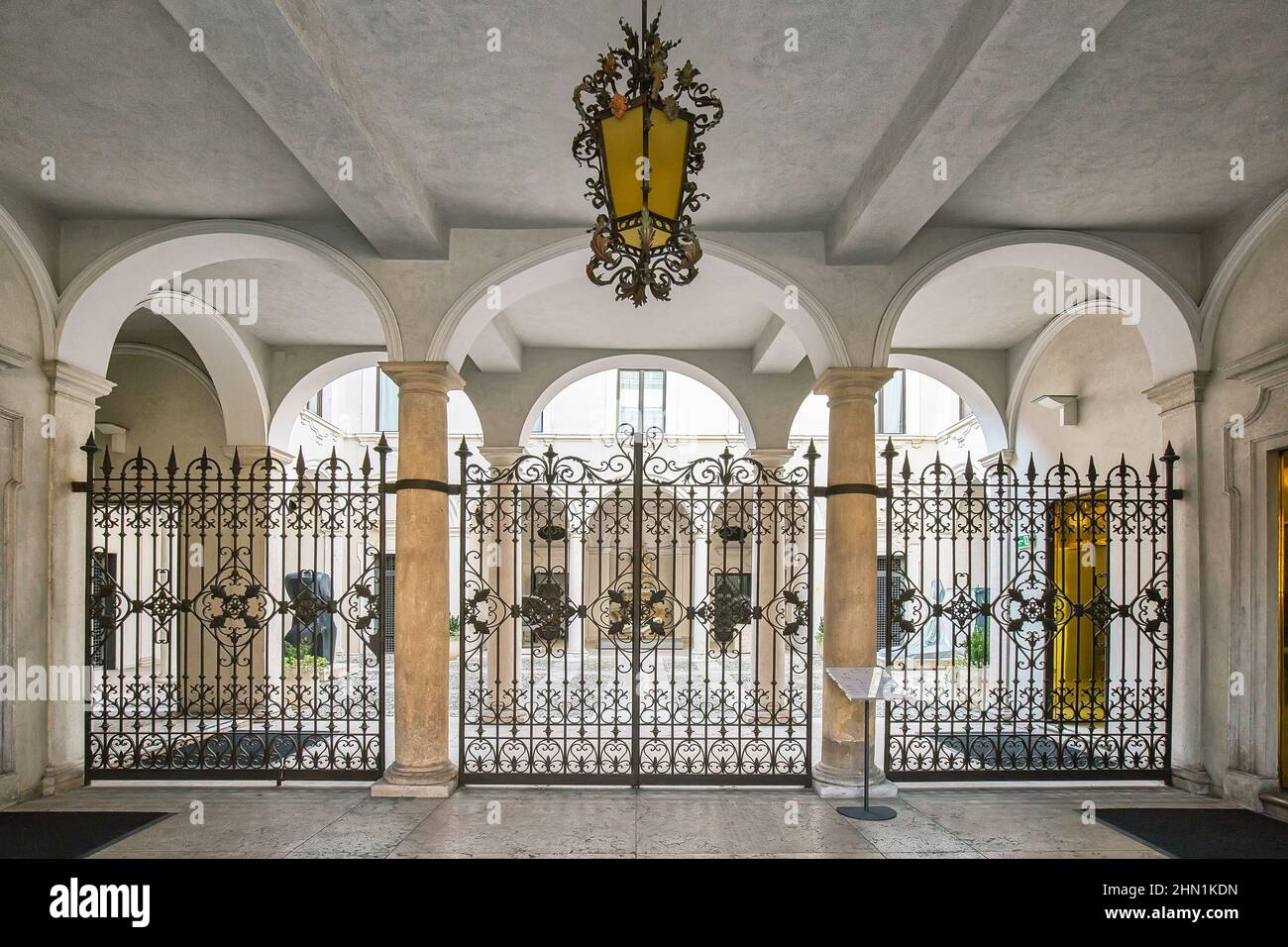Bellissimo cortile con archi, cancello forgiato e un lampadario sospeso Foto Stock