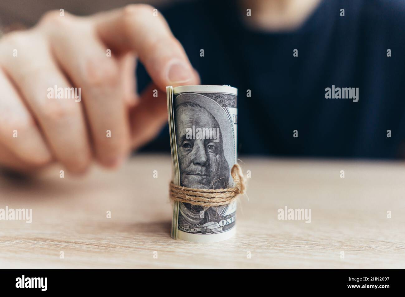 La persona punta ad una pila rotolata delle fatture del dollaro. Il concetto del primo denaro guadagnato. Foto Stock