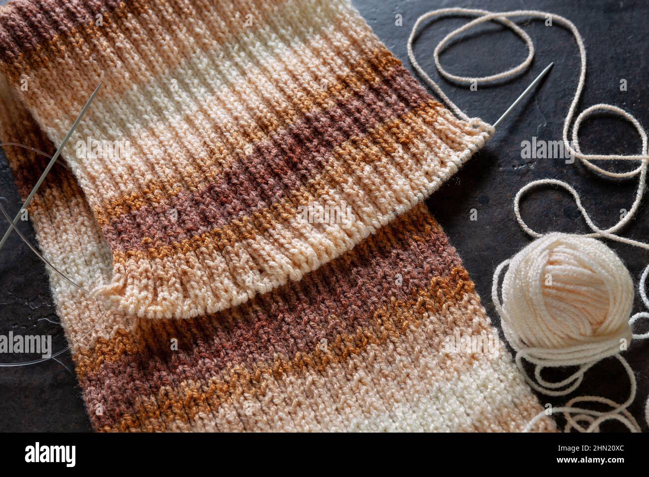 Progetto di maglia incompleto con aghi circolari. Filato lavorato a maglia con effetto gradiente, melange, tessuto texture tessuto macro pattern sfondo Foto Stock