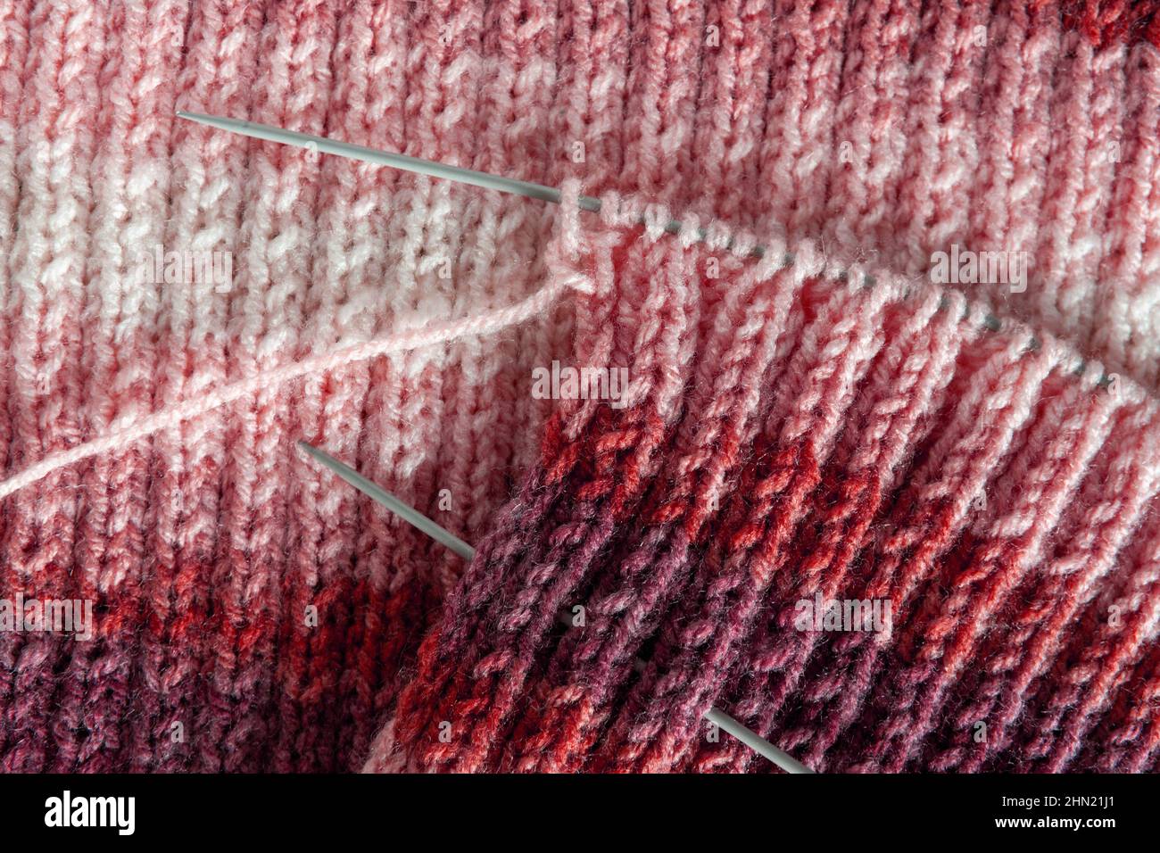 Progetto di maglia incompleto con aghi circolari. Filato lavorato a maglia con effetto gradiente, melange, tessuto texture tessuto macro pattern sfondo Foto Stock