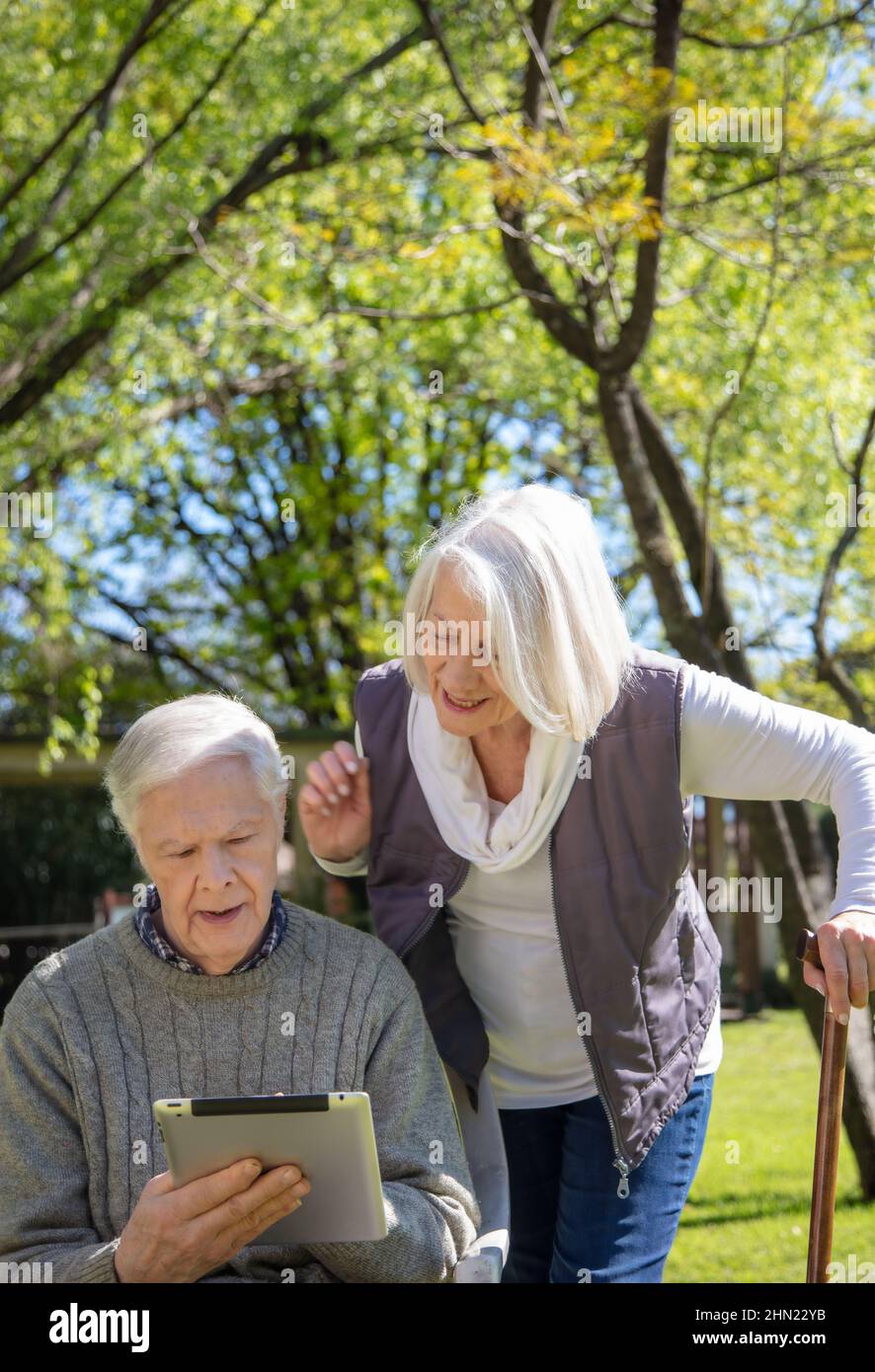 Coppia di anziani caucasici all'aperto giocando con tablet. Anziani pensionati che vivono la loro vita al suo meglio Foto Stock