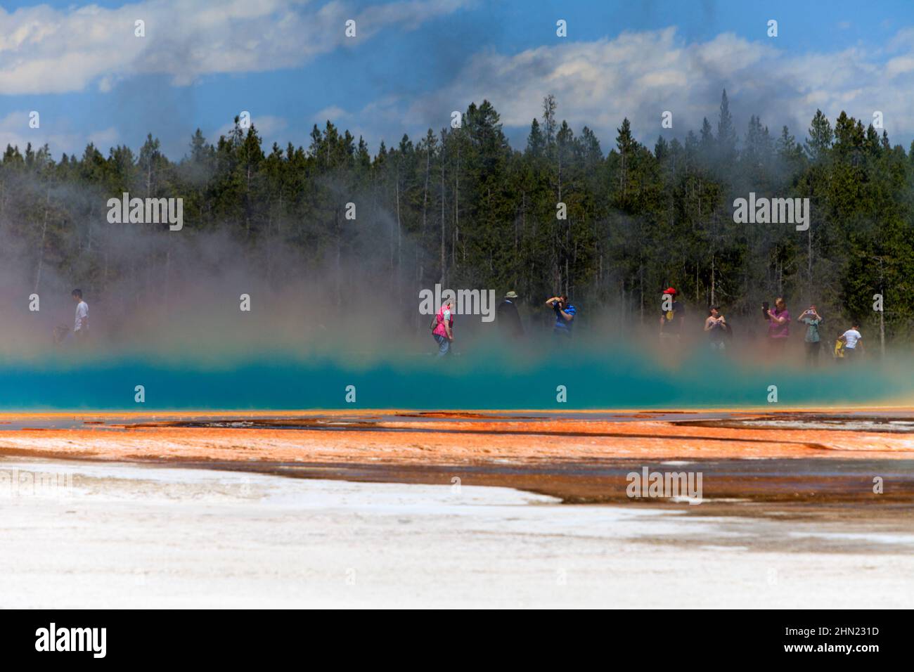 I turisti si sono avvolti di vapore che si innalza dalla sorgente prismatica Grand, dal bacino del geyser Midway, da Yellowstone NP, Wyoming Foto Stock