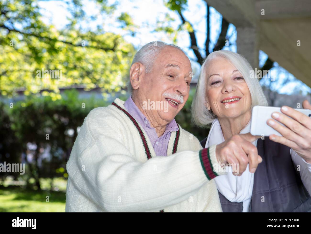 Felice coppia di anziani sorridenti prendendo selfie all'aperto. Anziani pensionati che vivono la loro vita al suo meglio Foto Stock