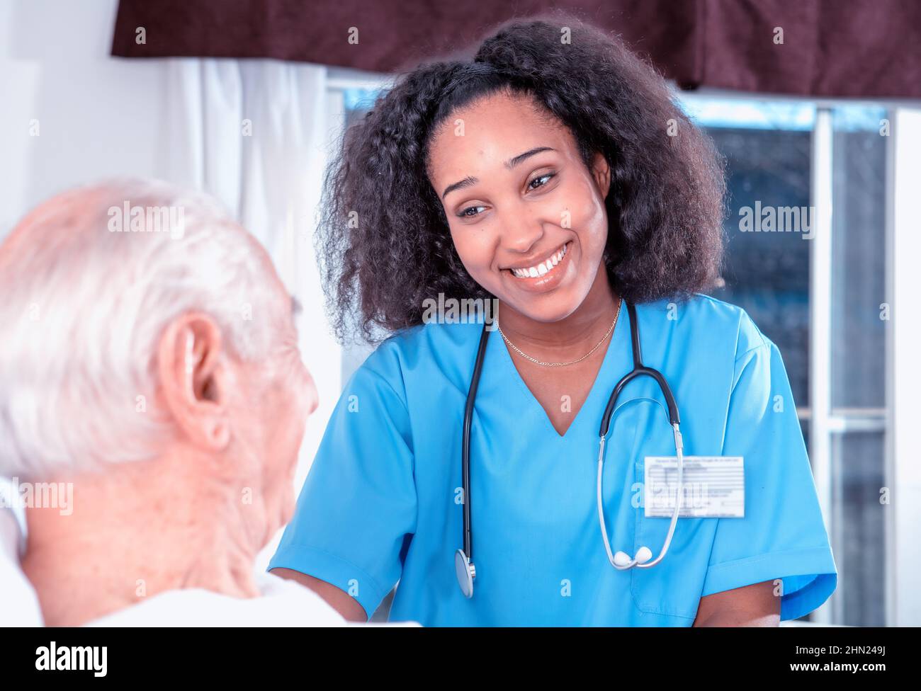 Caucasico maschio anziano sorridente con medico africano femmina all'ospedale. Anziani pensionati che vivono la loro vita al suo meglio Foto Stock