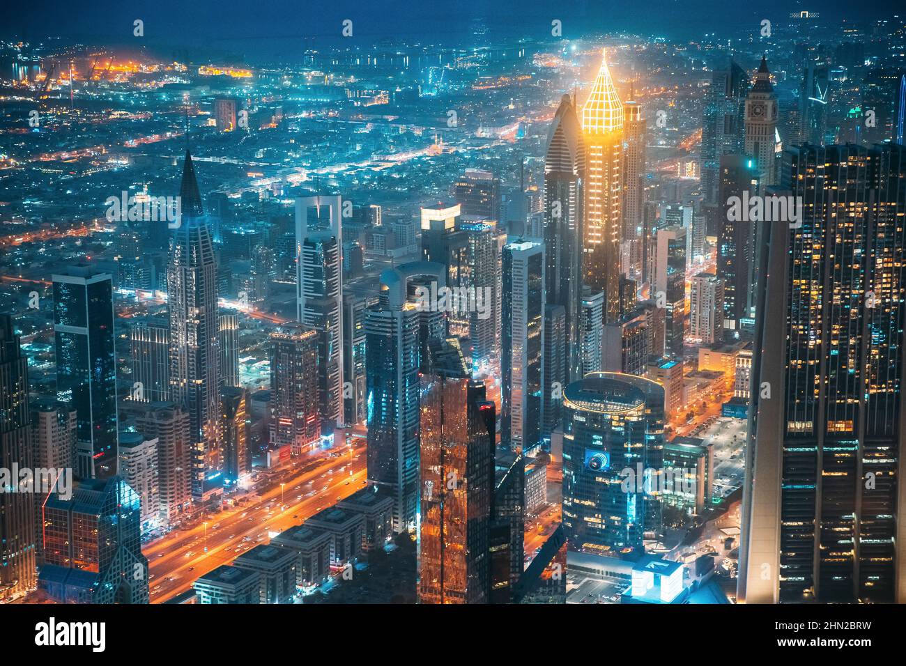 Vista aerea dello sfondo cittadino di un paesaggio urbano illuminato con grattacieli e moderna architettura urbana nella città di Dubai. Traffico notturno di strada in Foto Stock