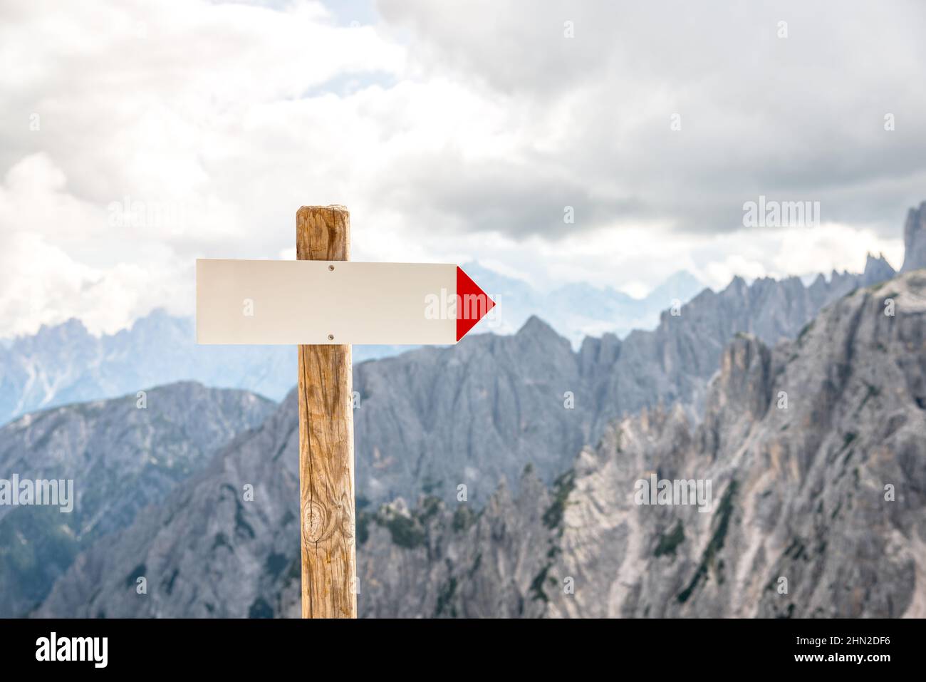 Primo piano del cartello direzionale bianco lungo un sentiero di montagna ad alta quota. Spazio di copia. Foto Stock