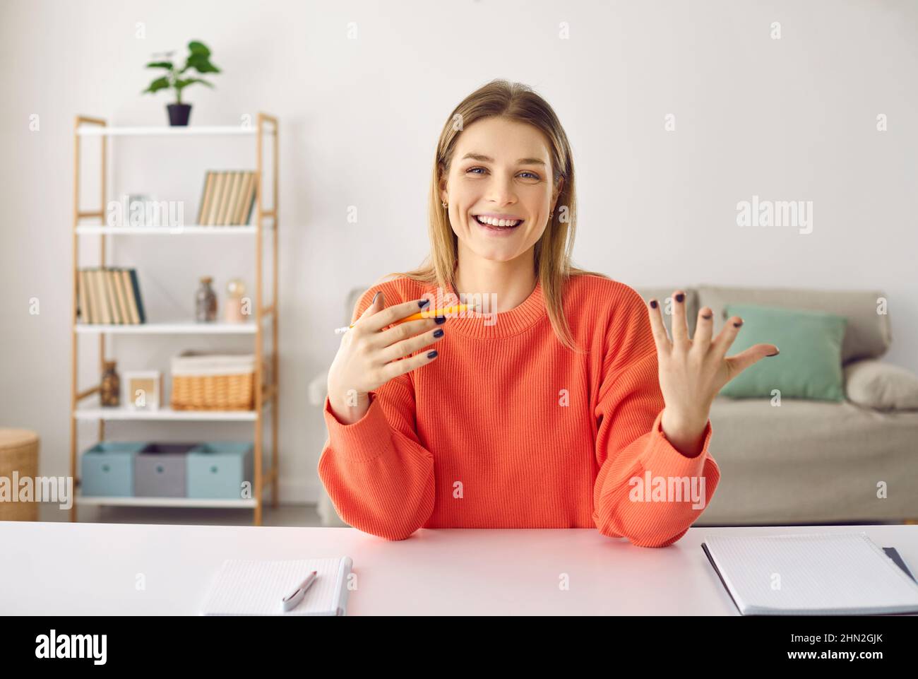 Donna positiva che parla e conduce consulenza online o formazione mentre si siede in ufficio a casa. Foto Stock