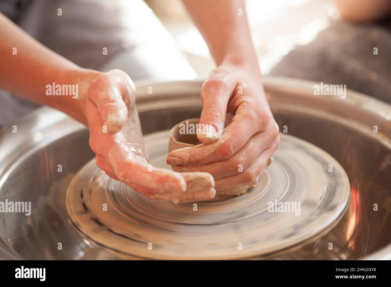Primo piano di mani di donna irriconoscibile che forma l'argilla sulla ruota vasai Foto Stock