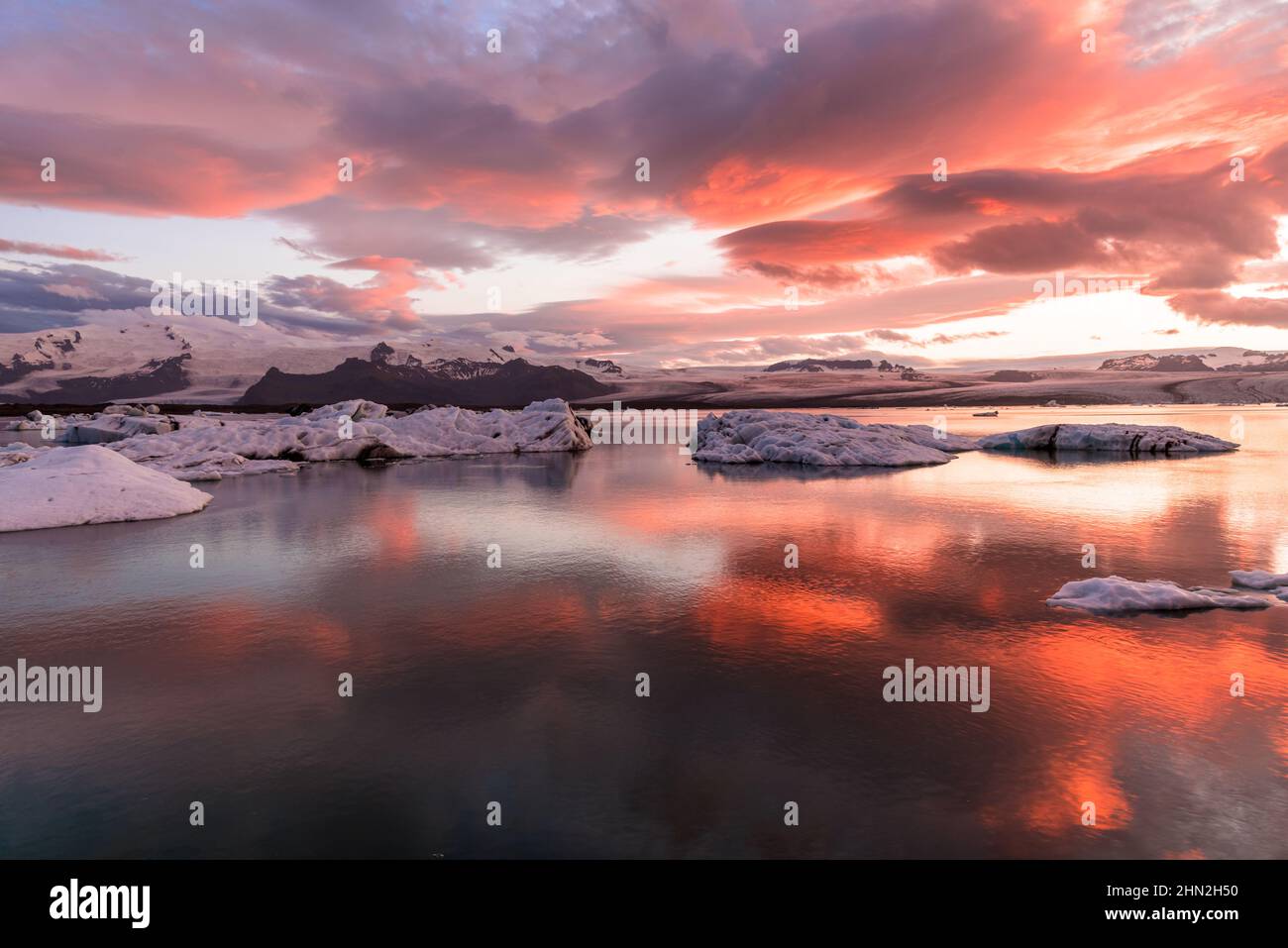 Vista di una laguna glaciale sotto un cielo drammatico al tramonto Foto Stock