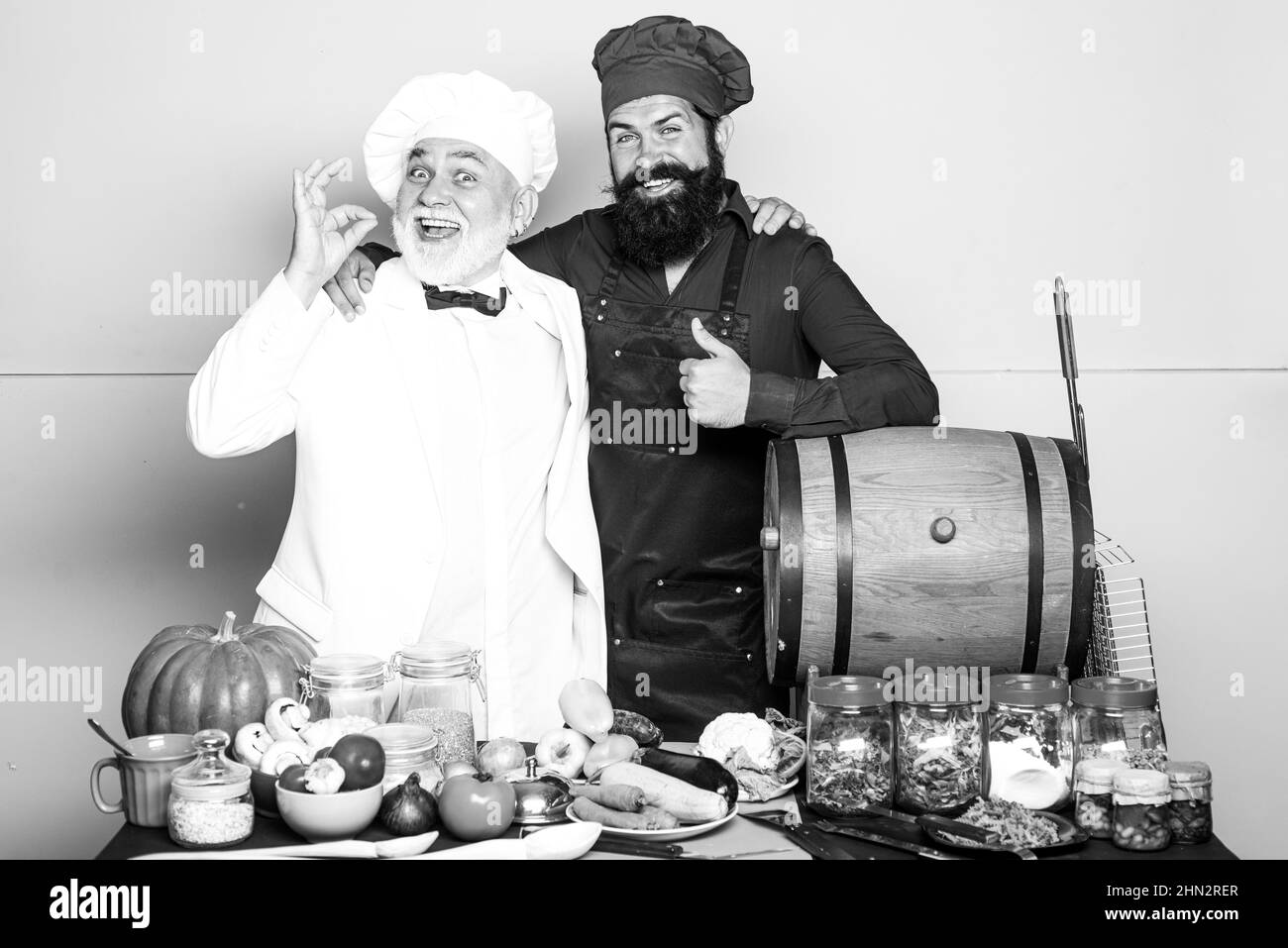 Chef professionista che mostra segno per deliziosi. Chef maschile in uniforme bianca con segno perfetto. Due bearded chef, cuoco o panettiere gesturing eccellente Foto Stock
