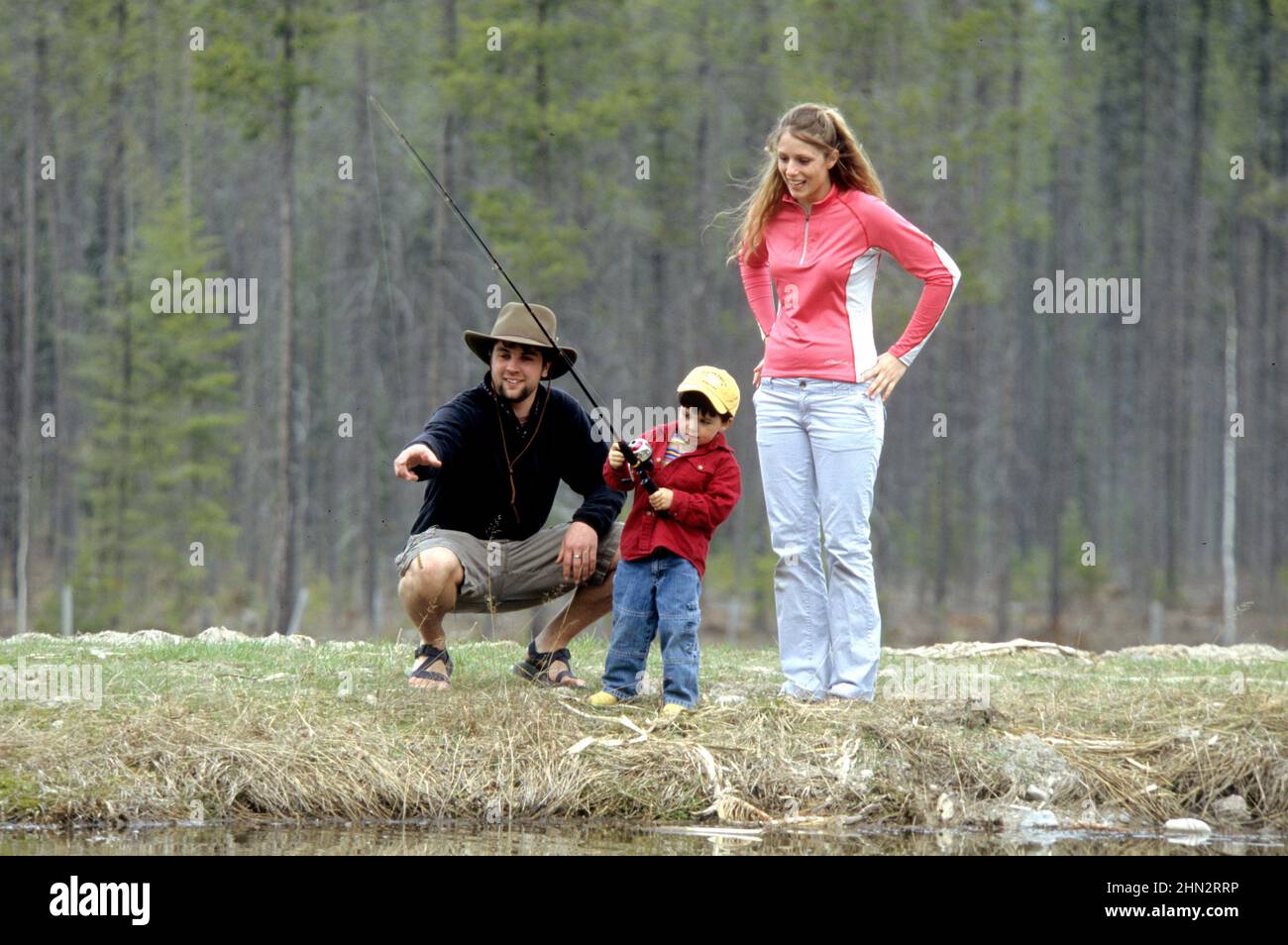 Genitori che insegnano a figlio giovane come pescare in un lago del Montana Foto Stock