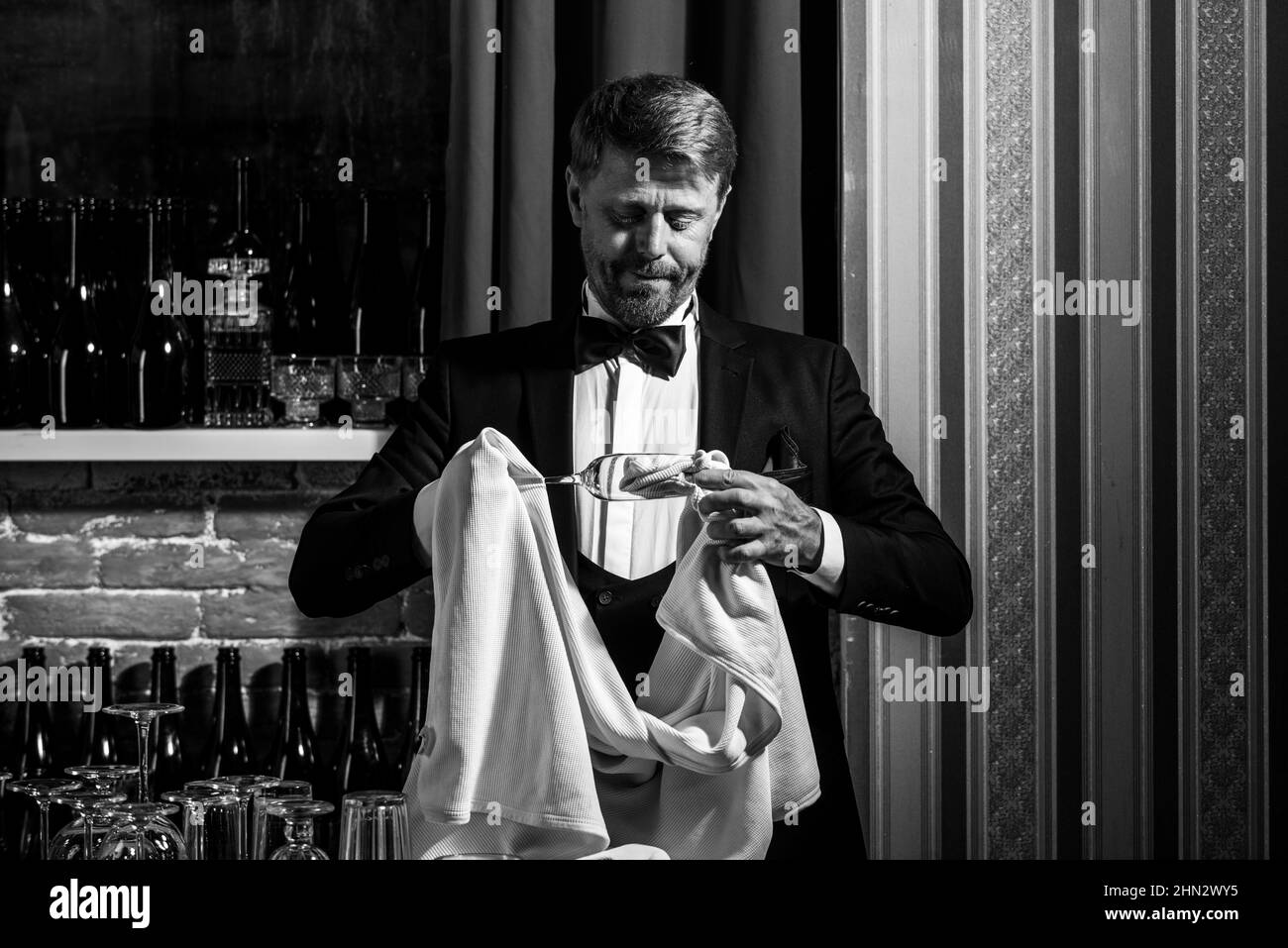 Vetro di sfregamento barista. Barman maschio in vetro pulito. Il personale del ristorante pulisce. Cameriere barista. Foto Stock