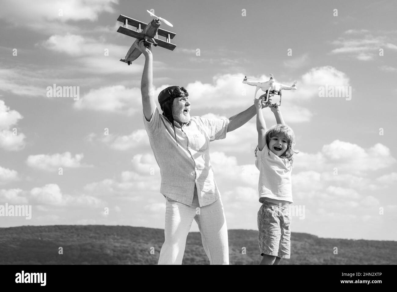 Nonno e figlio con aereo e quadricottero drone su cielo blu e sfondo nuvole. Anziano parente con bambino. Foto Stock