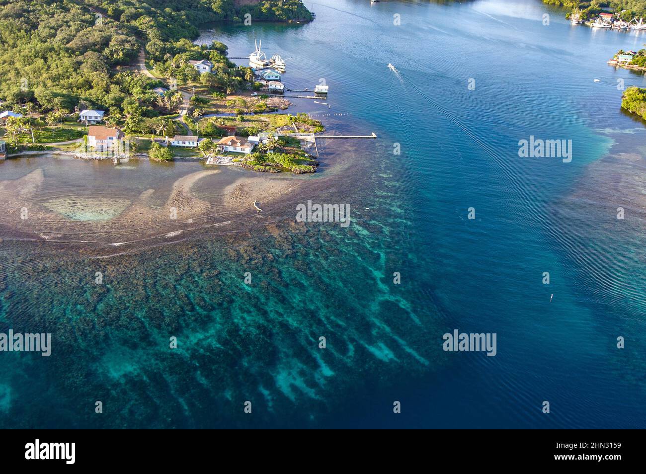 Una vista aerea di un canale sull'isola di Roatan mostra la barriera corallina che conduce ad una mensola di case abitate dai ricchi. Foto Stock
