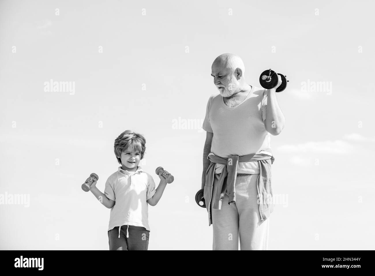 Uomo anziano e bambino nel club di salute della famiglia. Stile di vita sano. Nonno e nipote con manubri in mano. Sport per bambini piccoli. Foto Stock
