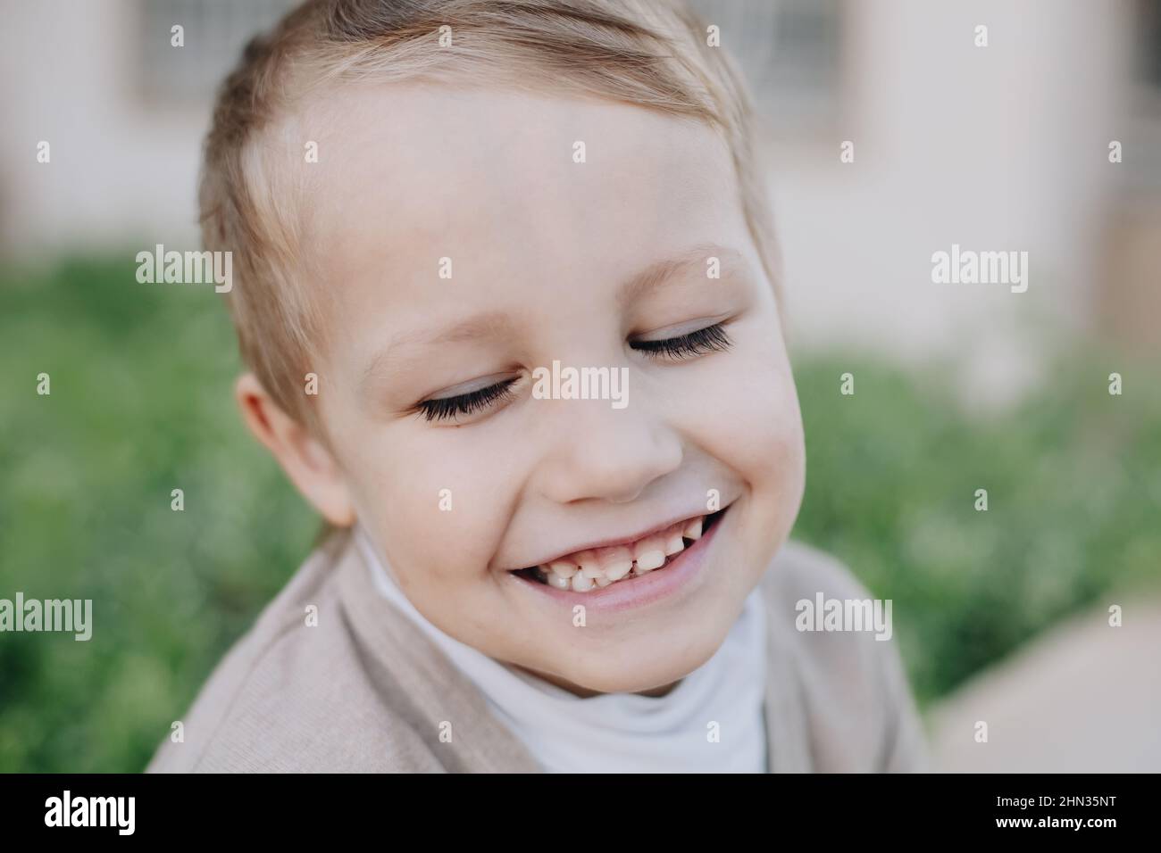 Faccia di bambino piccolo felice con gli occhi chiusi e sorridere con i denti del bambino Foto Stock