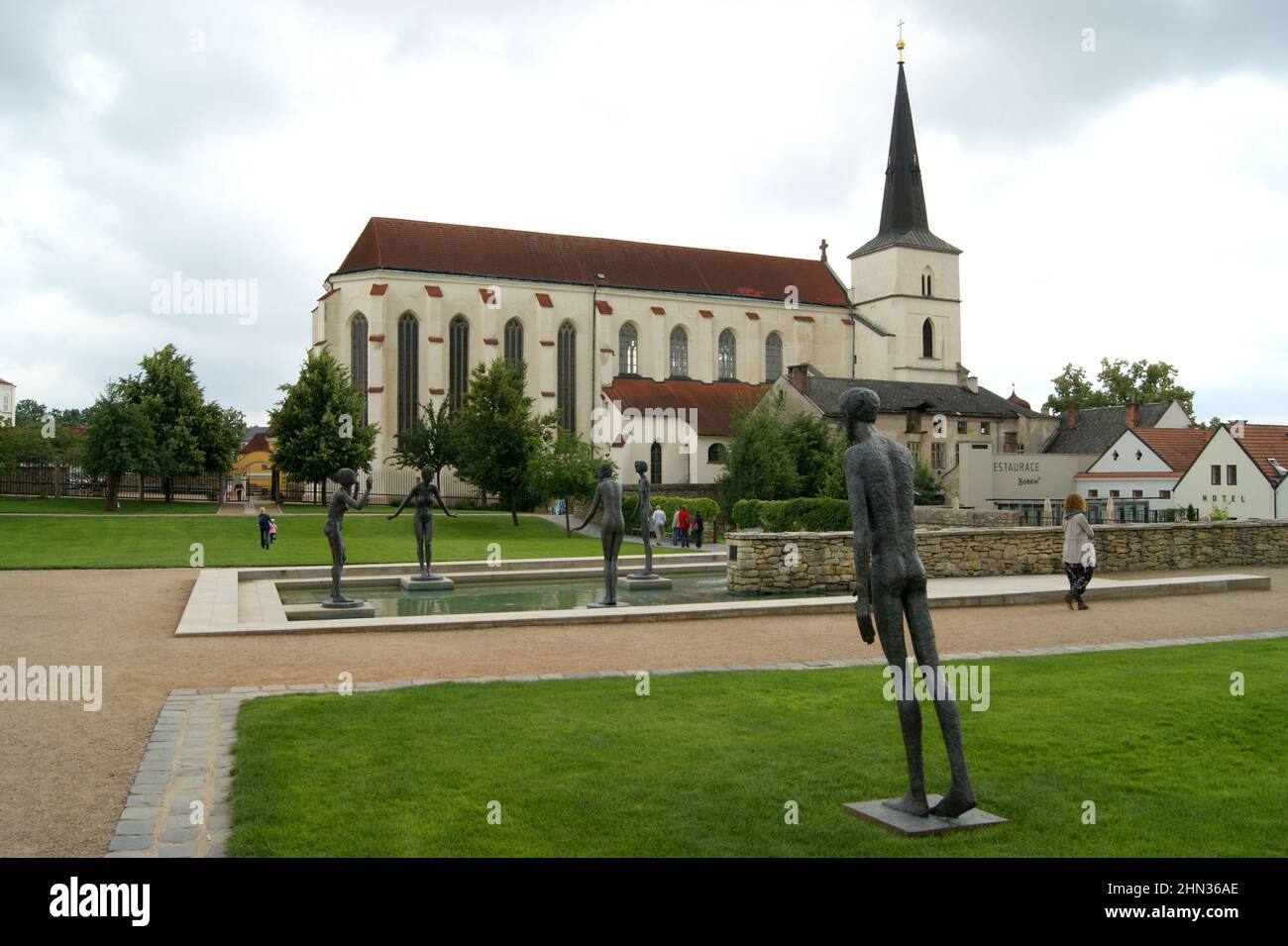 Piscina d'acqua con moderne sculture all'aperto, chiesa gotica e barocca dell'Esaltazione della Santa Croce sullo sfondo, Litomysl, Czechia Foto Stock