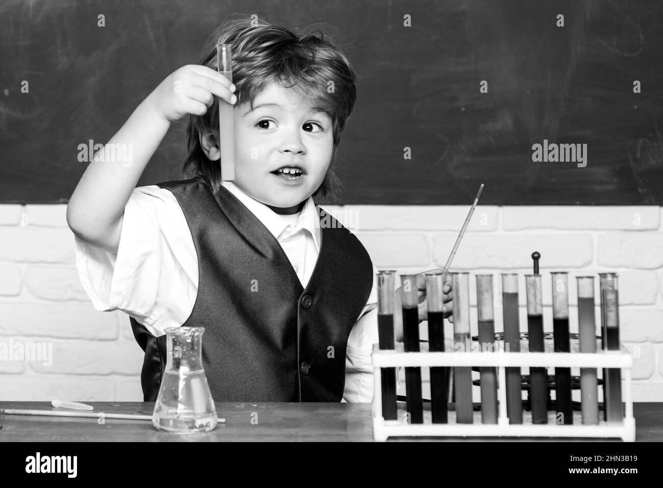 Torna a scuola. Preschooler. Hanno condotto un nuovo esperimento in chimica. Lezione di chimica. Il bambino sta imparando in classe sullo sfondo della lavagna Foto Stock