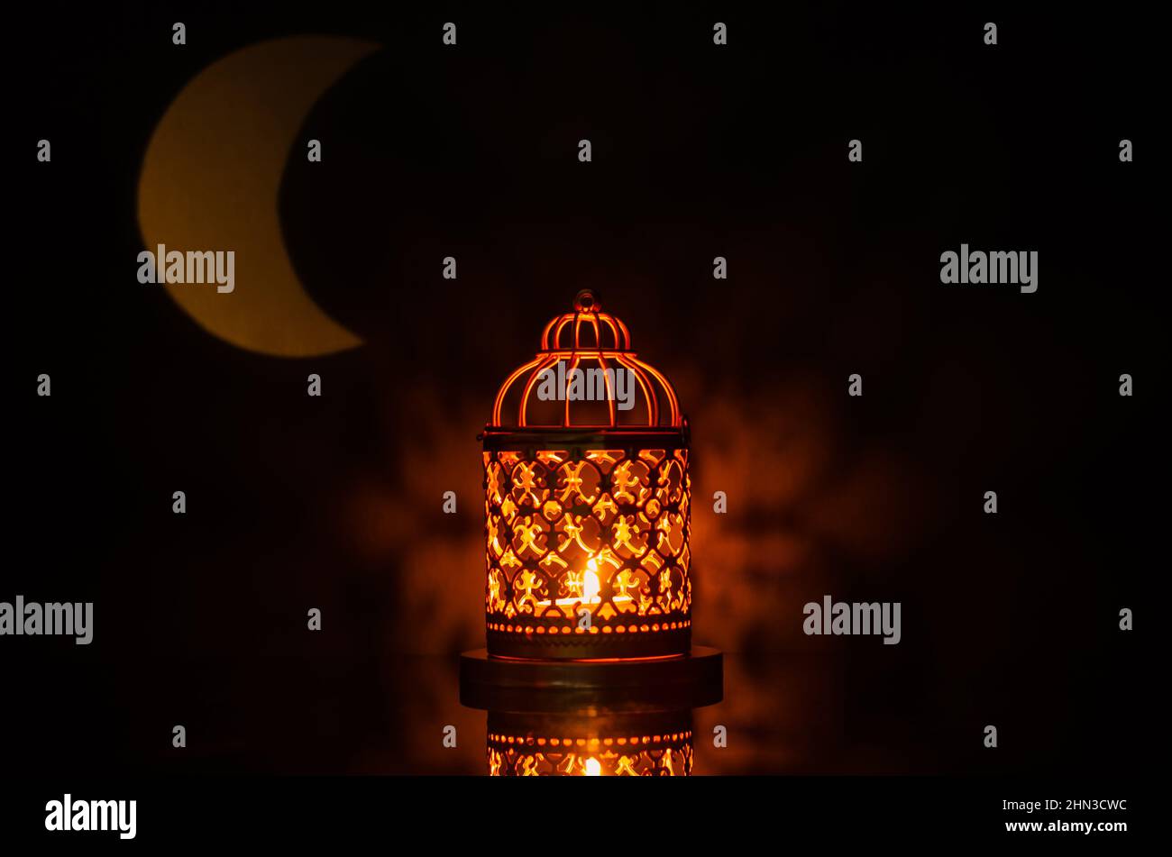 Fuoco selettivo della lanterna con la forma della luna dalla luce sullo sfondo per la festa musulmana del mese santo di Ramadan Kareem. Foto Stock