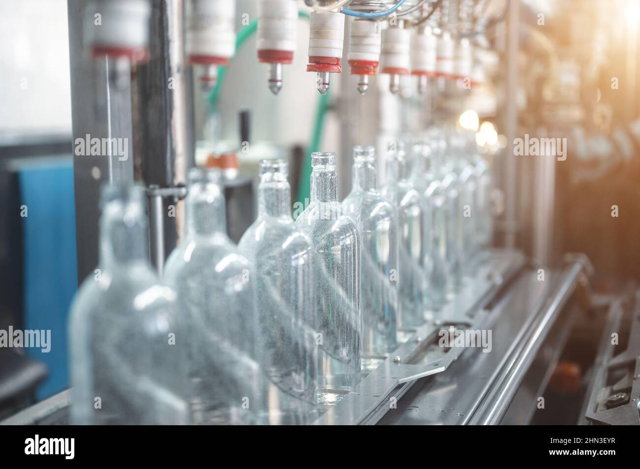 Riempimento di bottiglie di vetro con bevanda vodka sulla linea di produzione Foto Stock