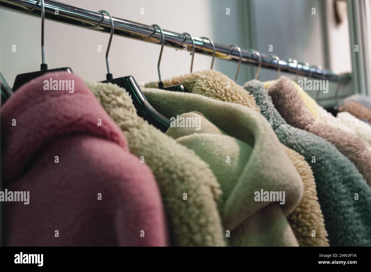 Eleganti cappotti e giacche in pelliccia sintetica appendono sul rack Foto Stock