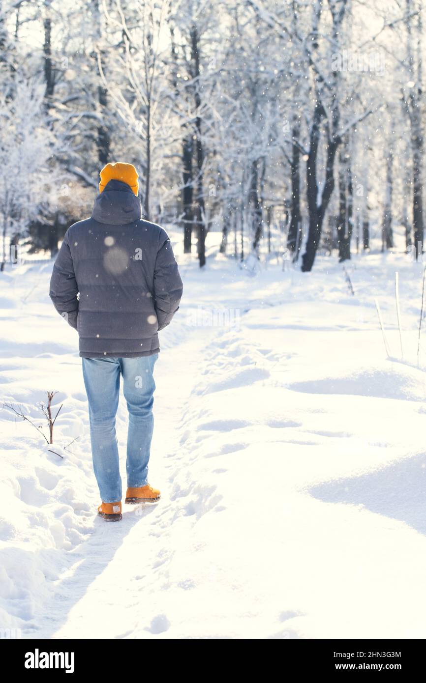 Un uomo cammina lungo un sentiero innevato fuori dalla città dopo una nevicata in una mattinata gelida. Russia, inverno. Foto Stock