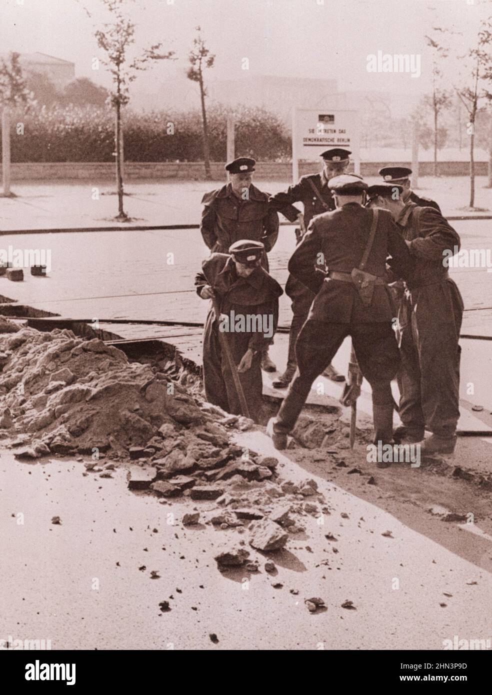 Foto d'epoca della crisi di Berlino del 1961: Costruire il muro della polizia tedesca orientale strappare marciapiede vicino Potsdamerplatz per costruire un blocco stradale permanente. Comu Foto Stock