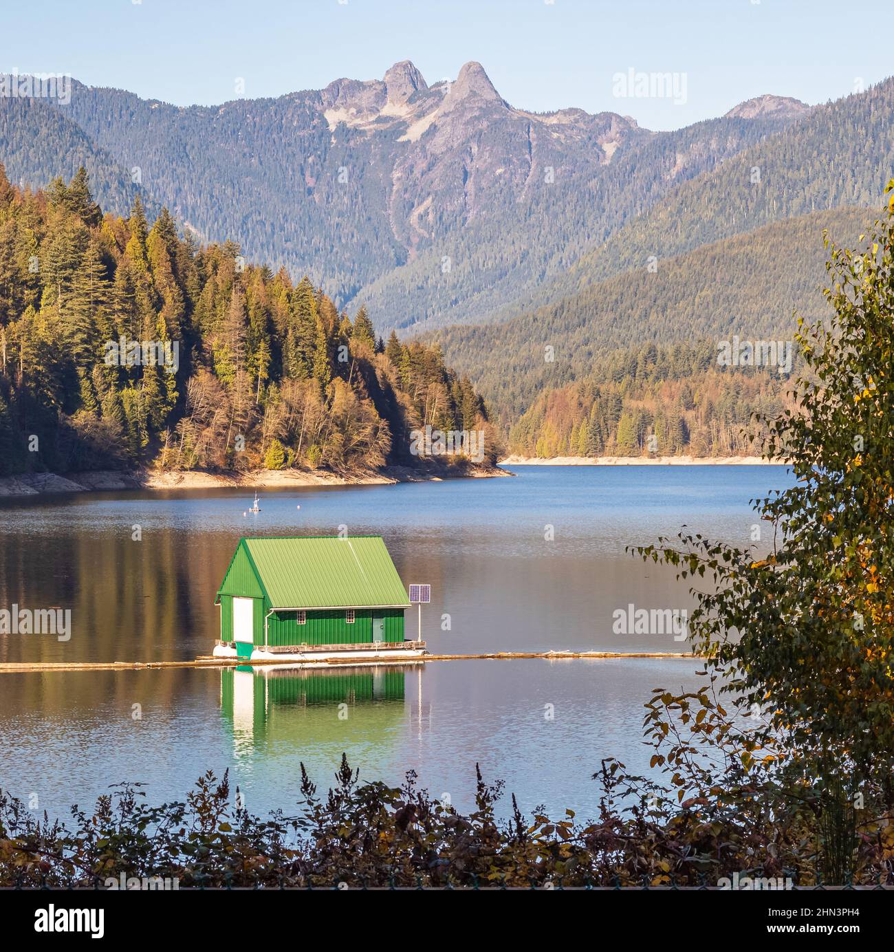 Splendido paesaggio autunnale di una casa di barche su un lago e le montagne a Cleveland Dam Reservoir vicino North Vancouver BC Foto Stock