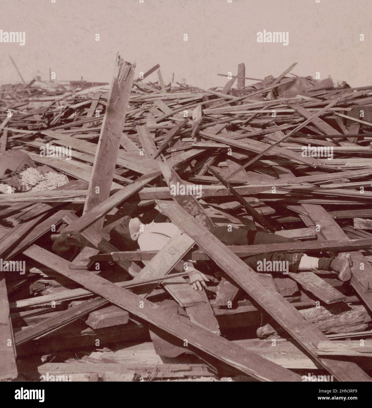 Foto d'epoca di Galveston Disaster, un uomo morto sotto un vasto mucchio di tavole di legno dopo l'uragano Galveston del 1900. USA Foto Stock