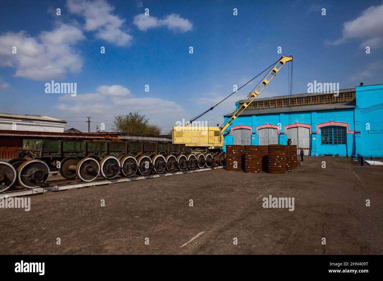 Impianto di riparazione locomotiva. Edificio del deposito Blue Vintage. Ruote del treno arrugginite a sinistra sull'asse e in pile al centro. Foto Stock