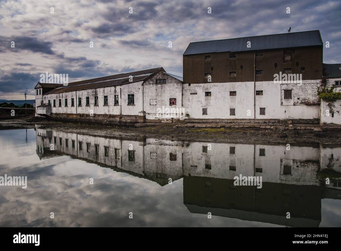 Spettrale fiume Vartry nel porto industriale di Wicklow città con vecchi edifici portuali che riflettono sul porto tranquillo, acqua piatta o inquietante abbandonato villaggio porto Foto Stock