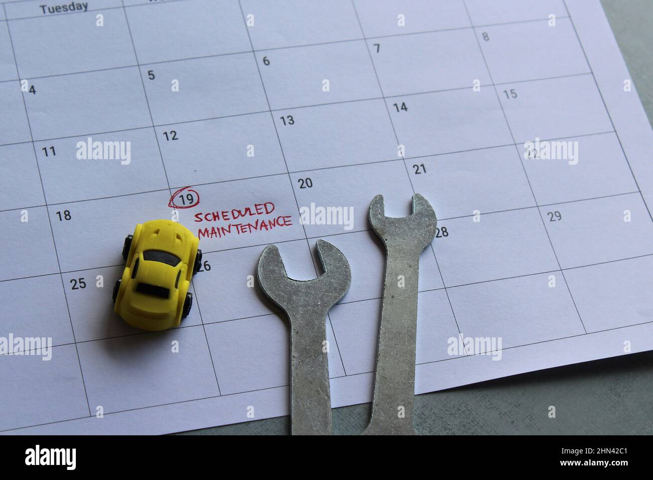 Concetto di manutenzione programmata del veicolo. Auto giocattolo, chiave e calendario con testo MANUTENZIONE PROGRAMMATA Foto Stock