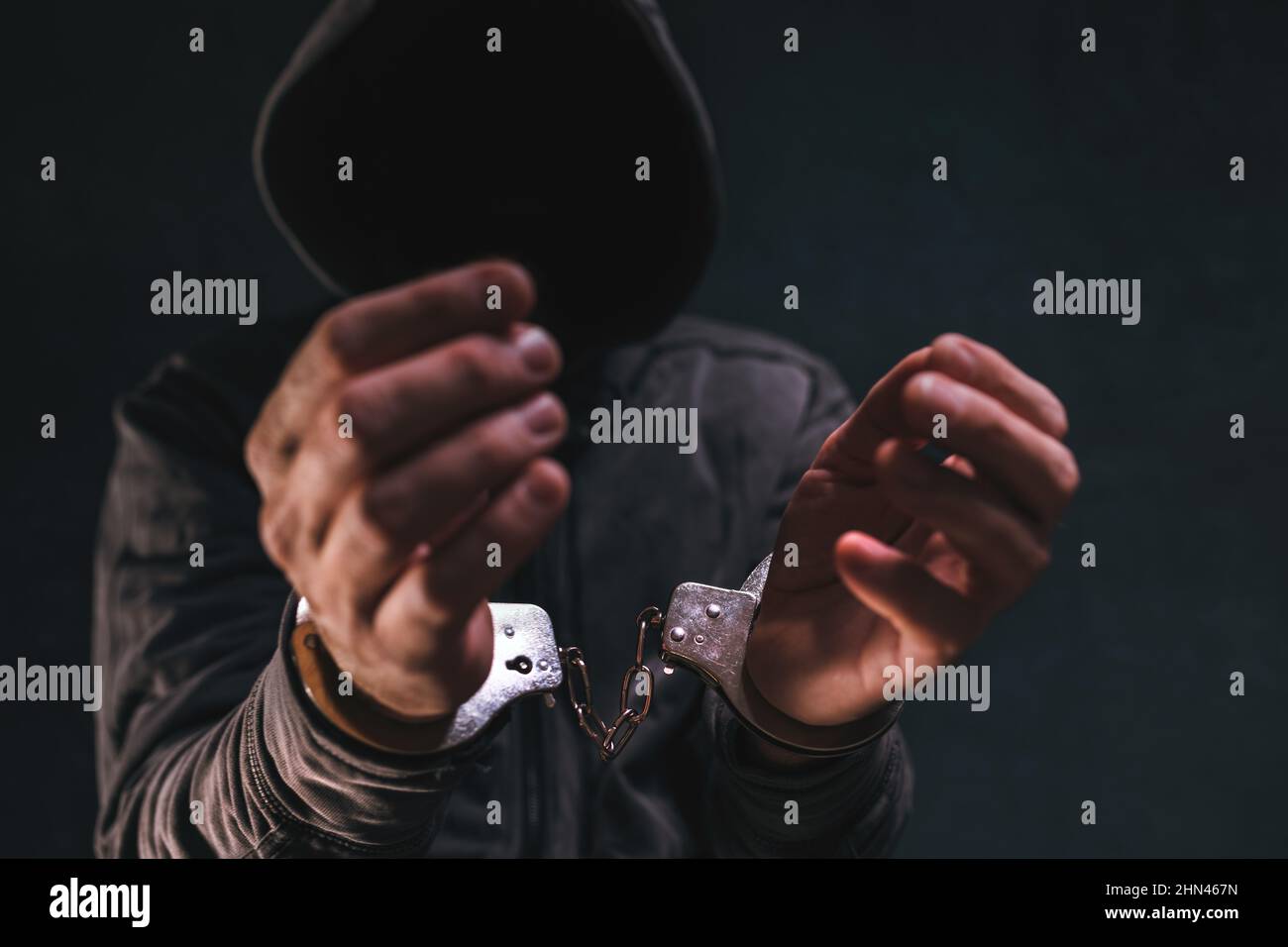 Criminale manicato con cappuccio e volto oscurato, unriconoscibile hooligan è arrestato, fuoco selettivo Foto Stock